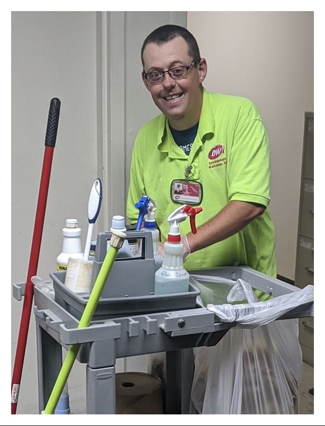 Smiling young man with custodial cart of equipment